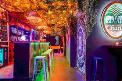 Miniature Location salle Lille (Nord) - Fullmoon #13 Façade d'un bar avec une décoration végétale, des néons roses et des tabourets noirs sur le trottoir.