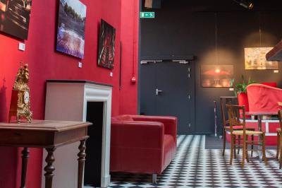 Espace salon avec canapés et fauteuils rouges, table basse en bois, plantes et photos encadrées sur un mur sombre.