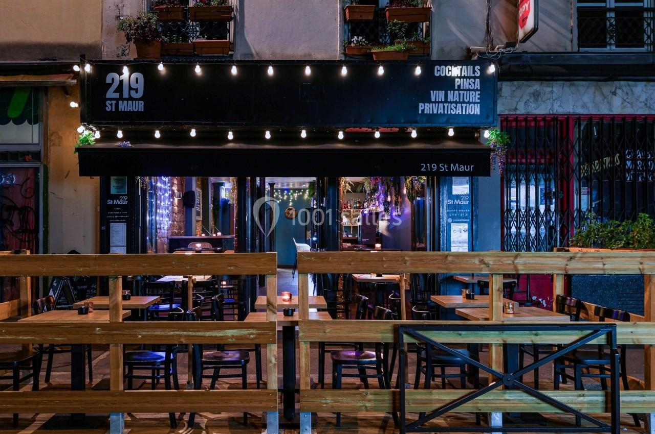 Façade d'un bar-restaurant avec terrasse en bois, éclairage nocturne et enseigne ’219 St Maur’.