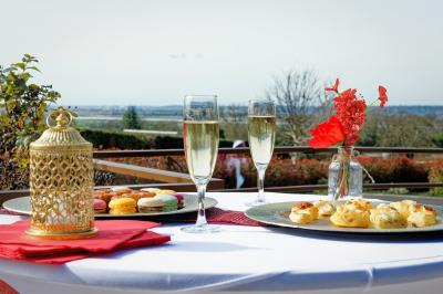 Aire de jeux en bois sur sol sablonneux, entourée de verdure et située près de bâtiments ruraux sous un ciel bleu.