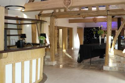 Aire de jeux en bois sur sol sablonneux, entourée de verdure et située près de bâtiments ruraux sous un ciel bleu.