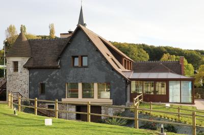 Aire de jeux en bois sur sol sablonneux, entourée de verdure et située près de bâtiments ruraux sous un ciel bleu.