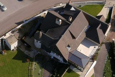 Aire de jeux en bois sur sol sablonneux, entourée de verdure et située près de bâtiments ruraux sous un ciel bleu.