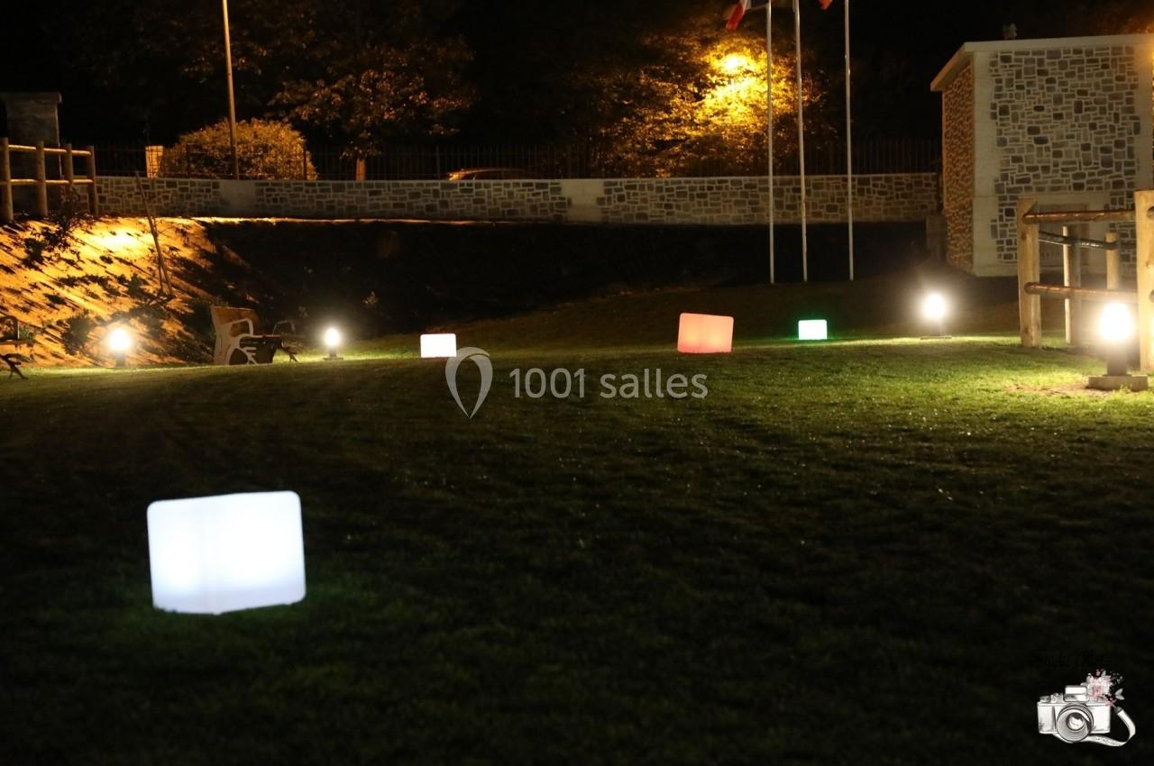 Pelouse éclairée la nuit avec des cubes lumineux colorés et des lampadaires en arrière-plan.