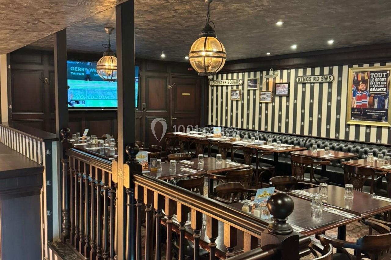 Salle de restaurant à l'étage avec tables dressées, décor rétro et murs ornés de cadres et affiches.
