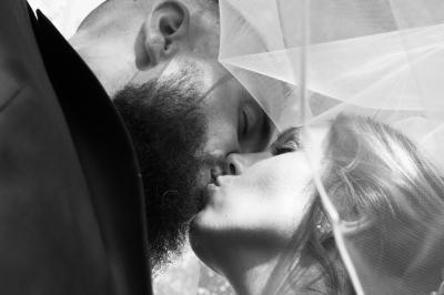 Un couple en tenue de mariage s'enlace dans un jardin verdoyant.