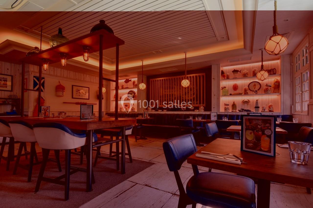 Une table ronde en bois clair avec des chaises assorties, dans une pièce lumineuse au plafond lambrissé.