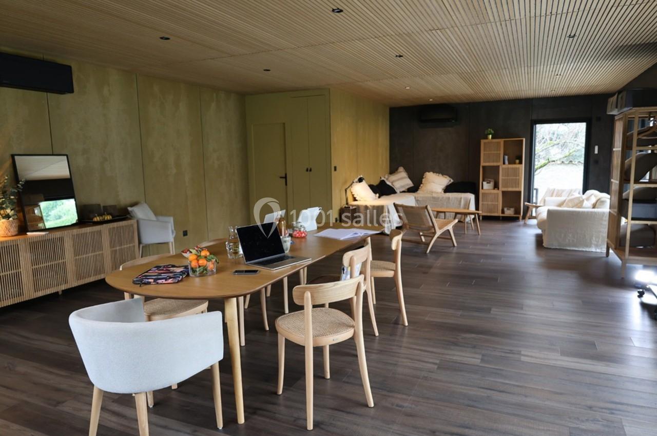 Salle de séjour lumineuse avec parquet, mobilier en bois clair, table de travail et coin salon confortable.
