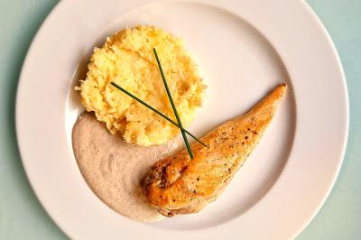 Miniature Filet de volaille jaune, crème aux champignons et purée de panais Plat dressé avec une base de viande effilochée, purée de pommes de terre, feuilles de salade et sauce en décoration.