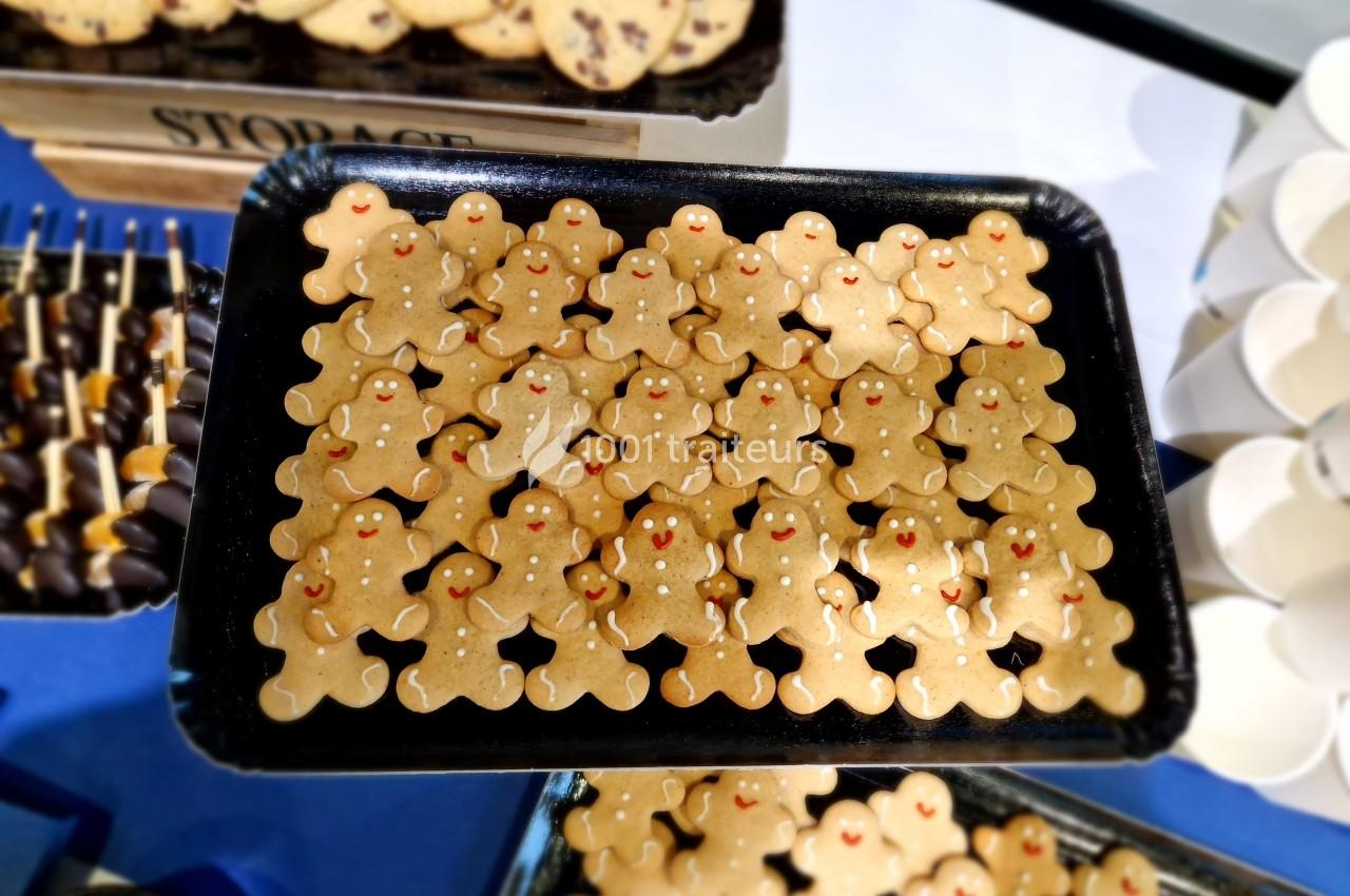 Plateau de biscuits en forme de bonshommes avec des décorations rouges, présenté sur une table.