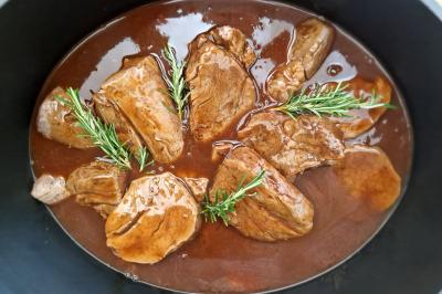 Plat dressé avec une base de viande effilochée, purée de pommes de terre, feuilles de salade et sauce en décoration.