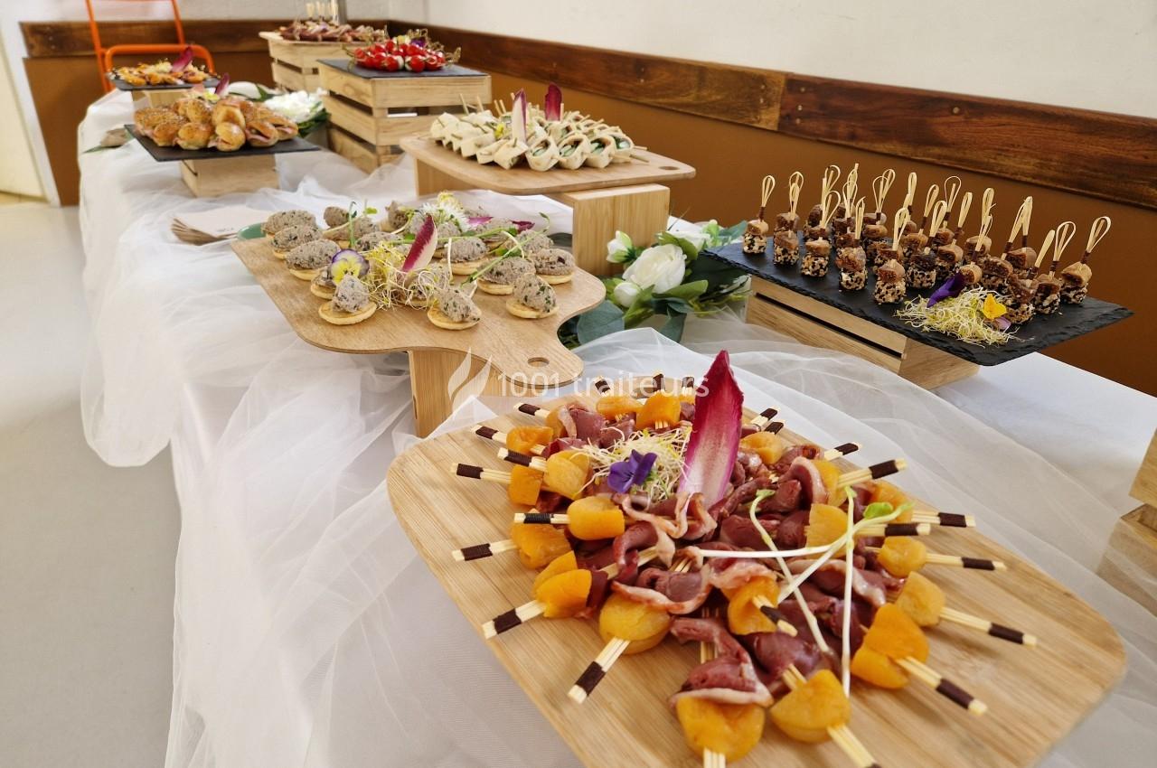 Buffet avec divers plats présentés sur des planches en bois, incluant charcuterie, canapés et desserts décorés.