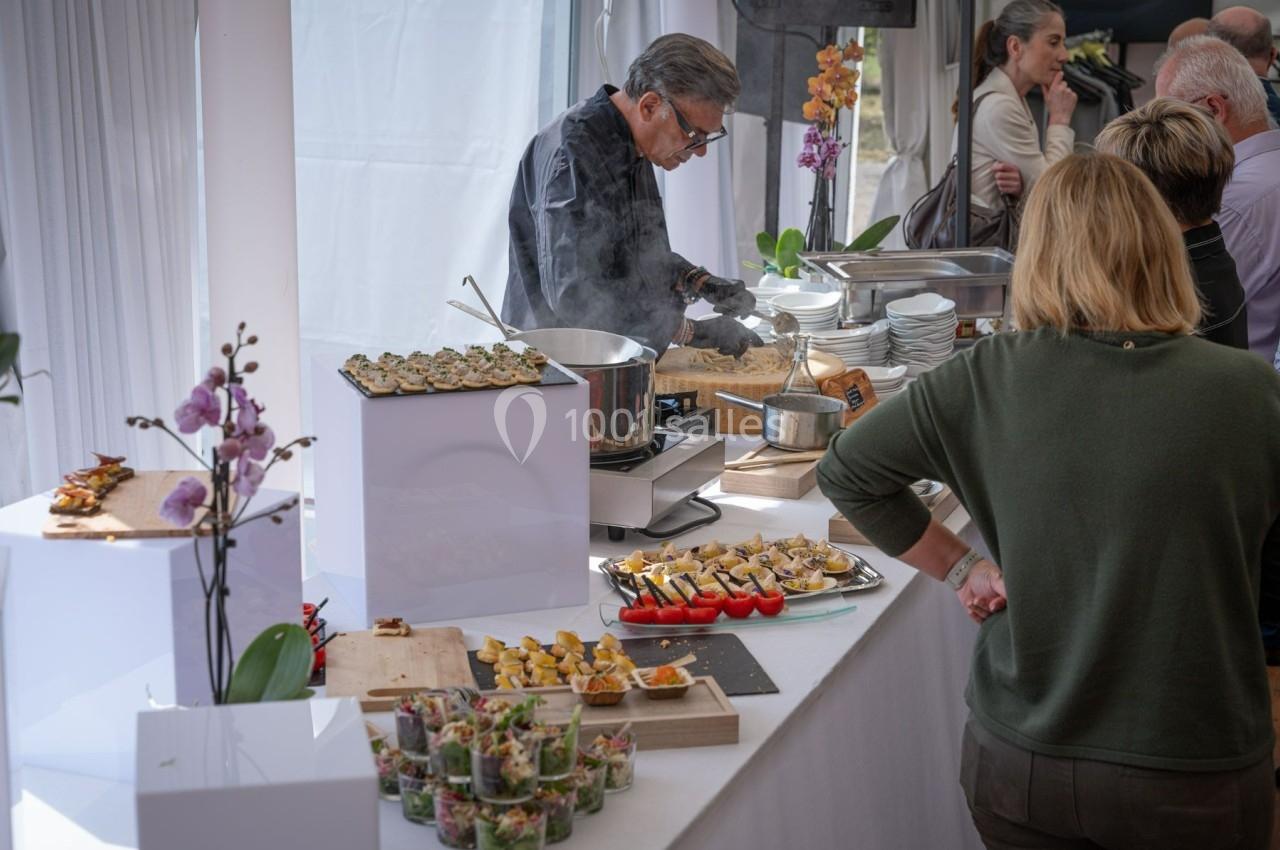 Un chef prépare des plats chauds lors d'un buffet avec des amuse-bouches et des décorations florales.