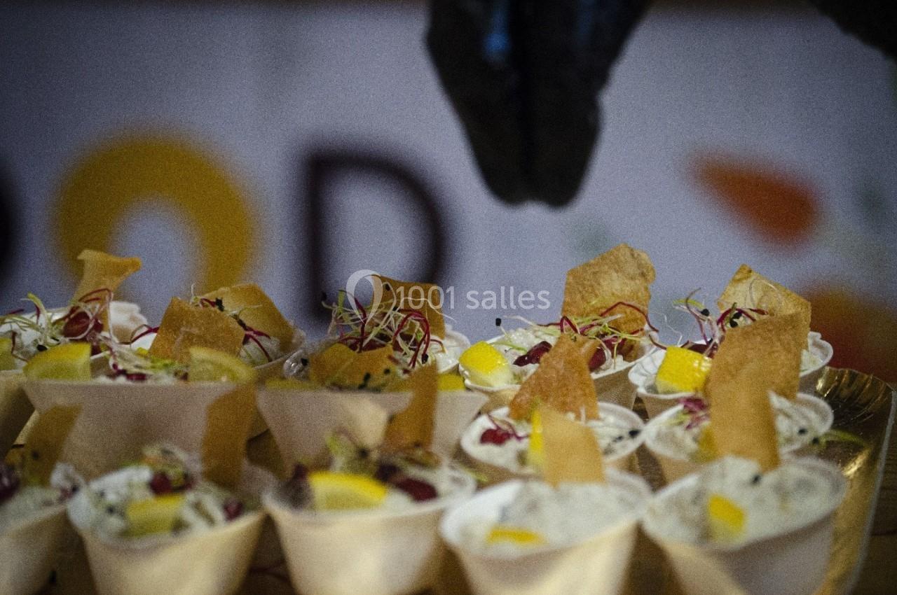 Coupes individuelles garnies de crème, morceaux de mangue, pousses et chips croustillantes, présentées sur un plateau.
