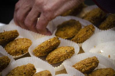 Assiette garnie de falafels dorés entourés de feuilles de salade et accompagnée de pinces en métal.