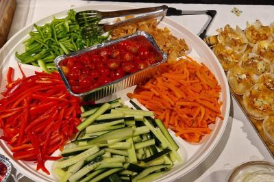 Assiette garnie de falafels dorés entourés de feuilles de salade et accompagnée de pinces en métal.