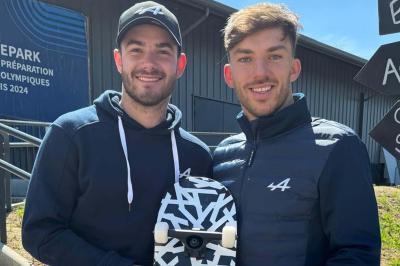Miniature Les Talents d'Espaces Réceptifs #4 Deux hommes souriants posent à l'extérieur, l'un tenant un skateboard noir et blanc devant un bâtiment moderne.