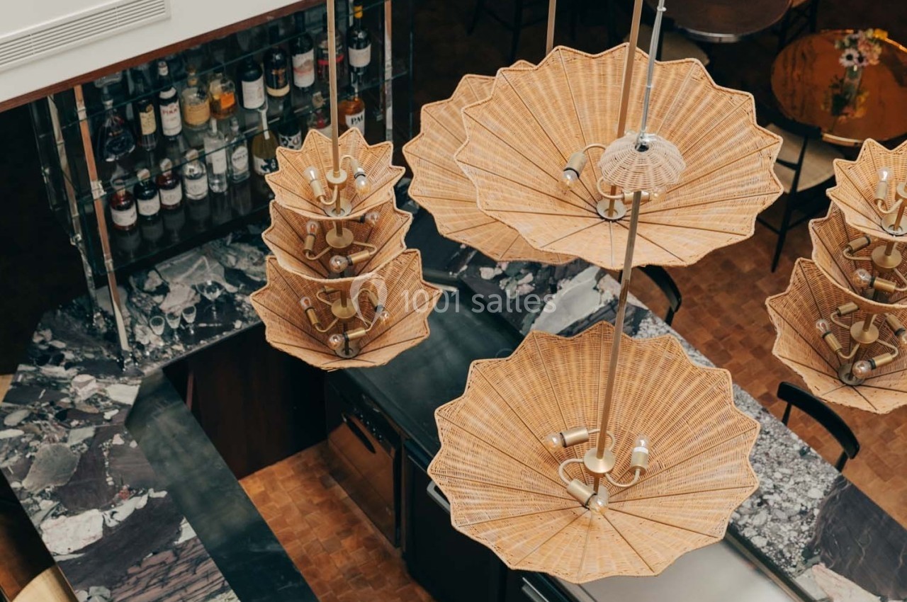 Suspensions en rotin en forme de parasols au-dessus d'un comptoir en marbre dans un espace intérieur élégant.