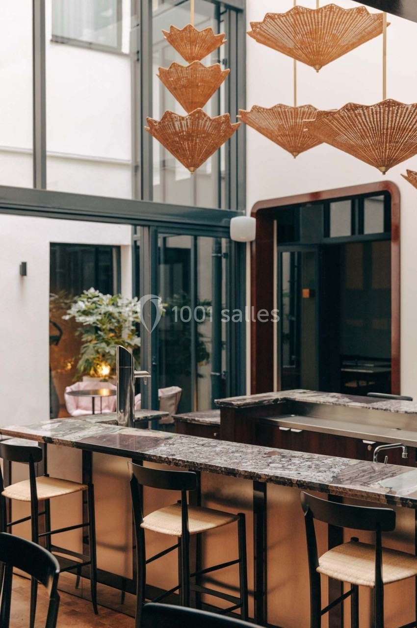 Cuisine moderne avec un îlot central en marbre, tabourets en bois et suspensions en forme d'éventails.