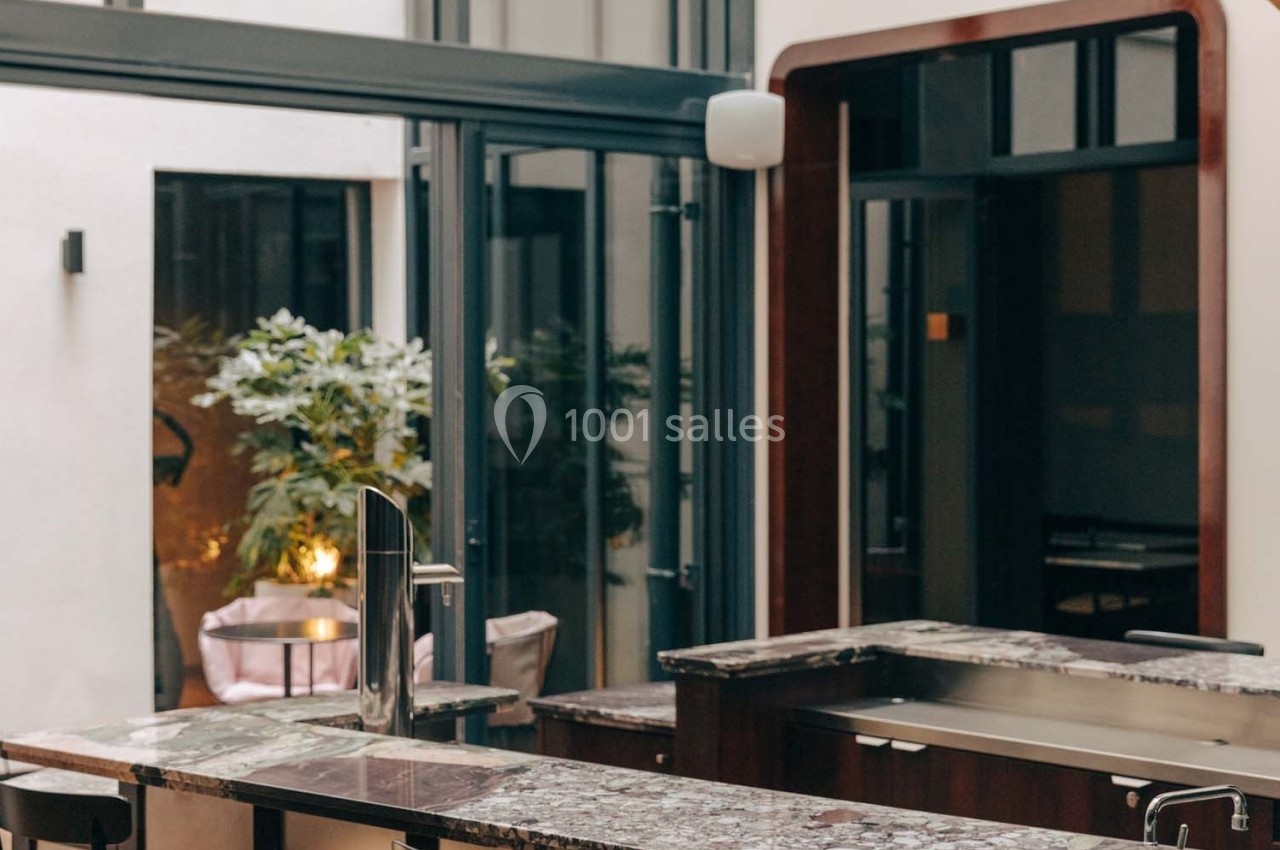 Cuisine moderne avec un plan de travail en marbre, un robinet design et de grandes baies vitrées donnant sur un patio.