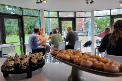 Quatre voitures sportives colorées alignées sur un parking en plein air, entourées de verdure.