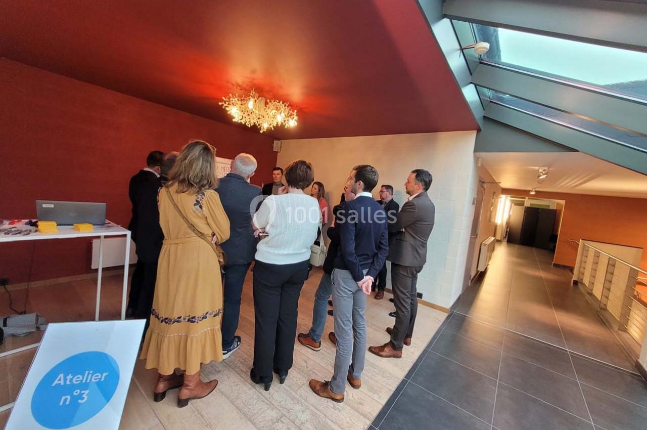 Un groupe de personnes debout en cercle dans une salle lumineuse, participant à une discussion ou un atelier.