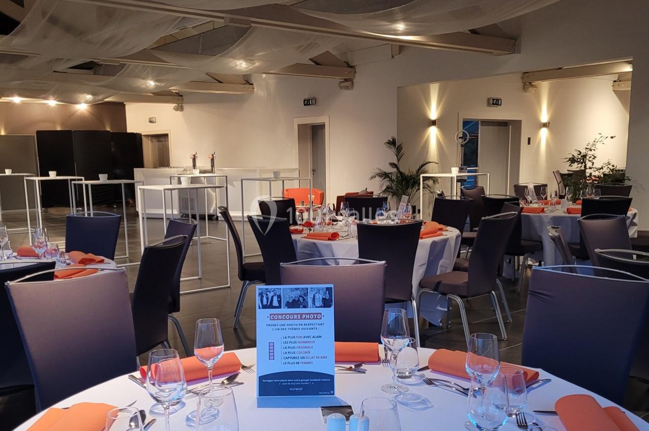 Salle de réception élégamment aménagée avec tables dressées, chaises violettes et décoration moderne.