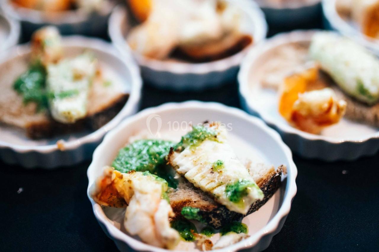 Assiette contenant des morceaux de poisson, crevettes et sauce verte, présentés sur des tranches de pain.