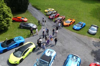 Quatre voitures sportives colorées alignées sur un parking en plein air, entourées de verdure.