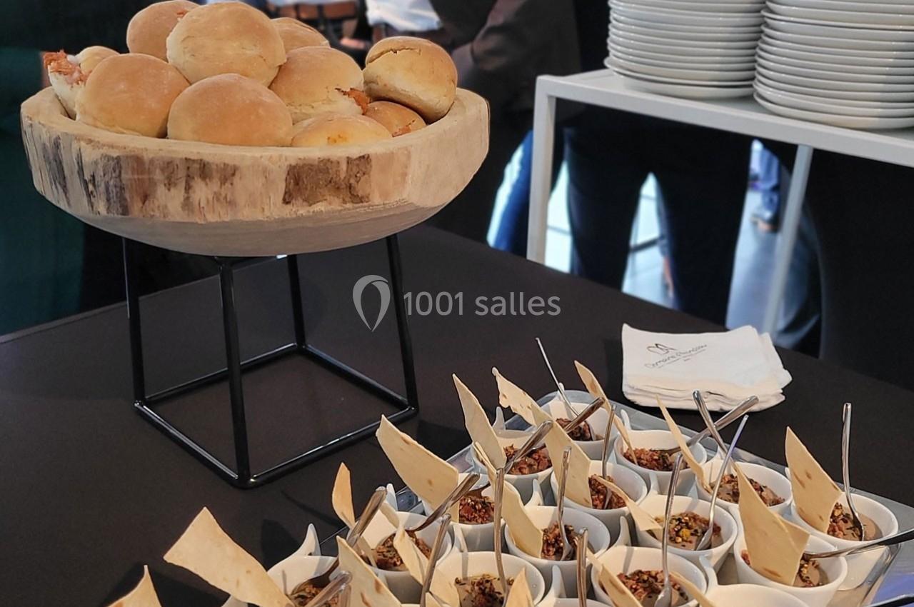 Plateau de petits pains et verrines garnies de chips et d'épices sur une table lors d'un événement.