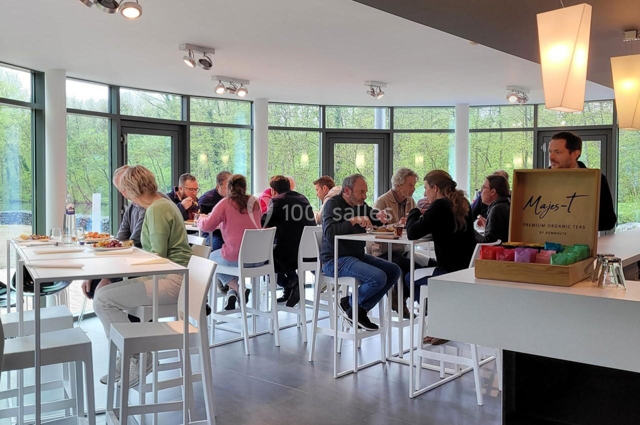Des personnes assises autour de tables hautes dans un espace lumineux, discutant et partageant un moment convivial.