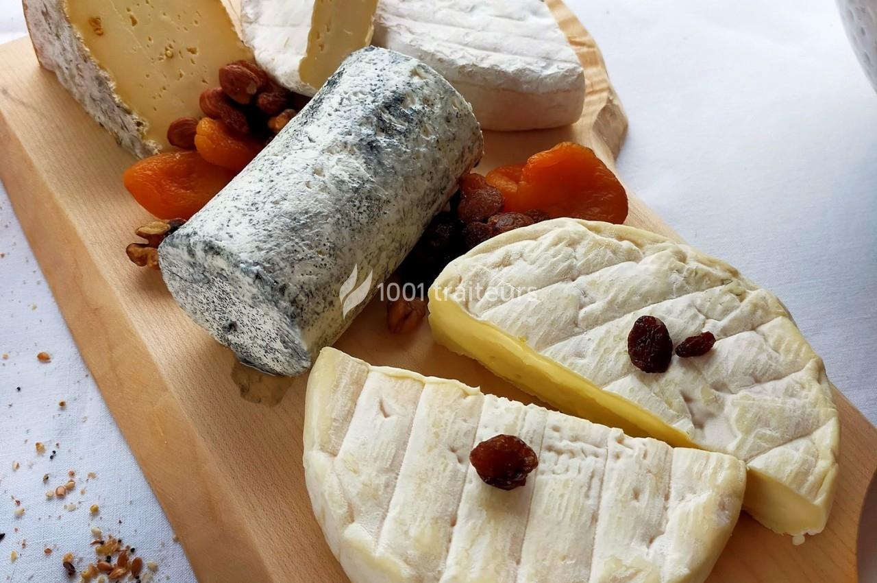 Plateau de fromages variés avec fruits secs et abricots sur une planche en bois.