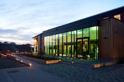 Exposition de véhicules Range Rover et Jaguar dans un showroom éclairé avec des fiches techniques visibles.
