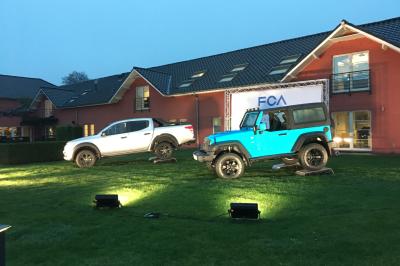 Exposition de véhicules Range Rover et Jaguar dans un showroom éclairé avec des fiches techniques visibles.