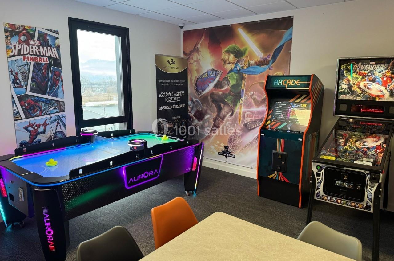 Salle de jeux avec un air hockey lumineux, bornes d'arcade rétro et affiches de jeux vidéo sur les murs.