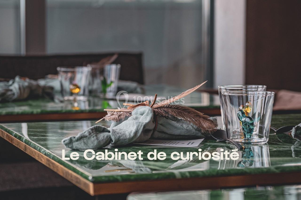 Table en marbre vert avec serviette pliée, plume décorative et verres, dans un cadre intérieur élégant.