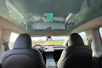 Intérieur d'une voiture avec sièges en cuir noir, écran tactile central et accoudoir avant.