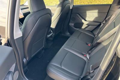 Intérieur d'une voiture avec sièges en cuir noir, écran tactile central et accoudoir avant.