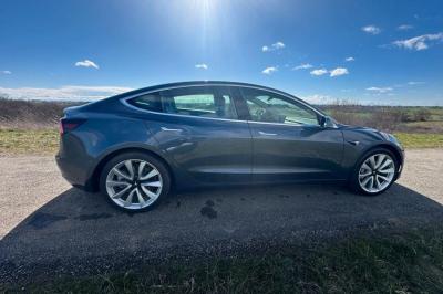 Intérieur d'une voiture avec sièges en cuir noir, écran tactile central et accoudoir avant.