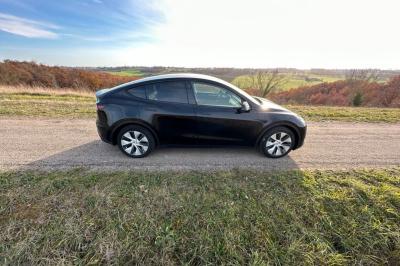 Intérieur d'une voiture avec sièges en cuir noir, écran tactile central et accoudoir avant.