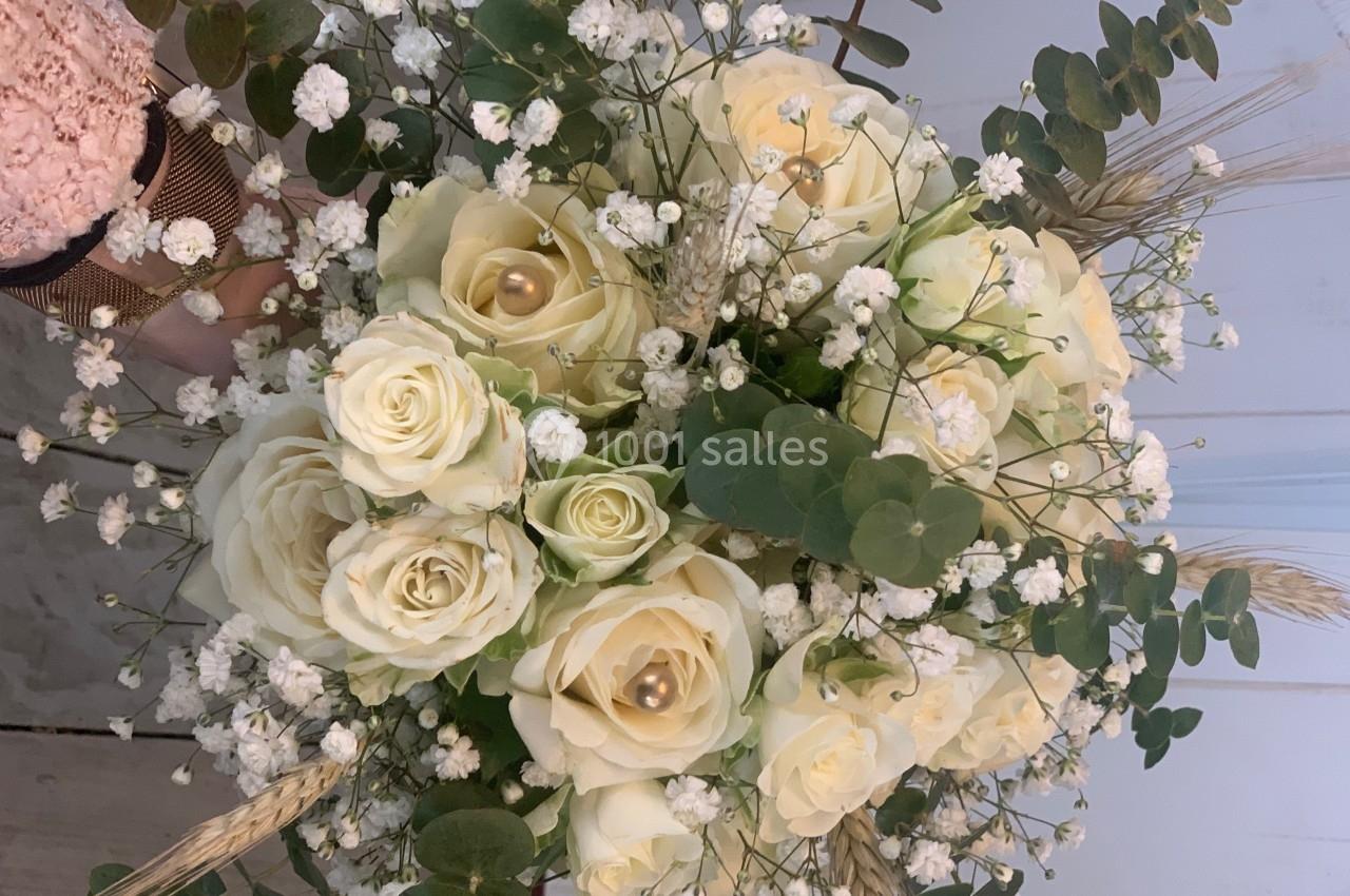 Bouquet de roses blanches entourées de gypsophiles, d'eucalyptus et d'épis de blé, disposé sur une surface claire.