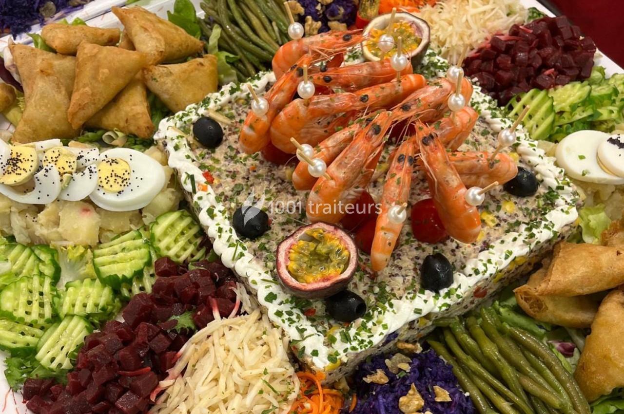 Plateau de buffet avec crevettes, samoussas, légumes variés, œufs durs et garnitures colorées.