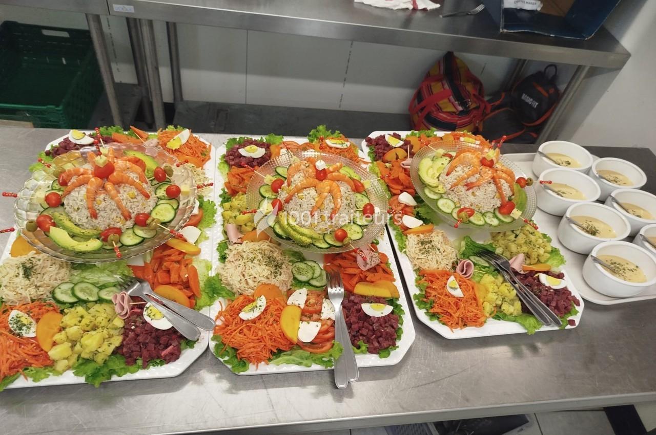 Plateaux de crudités variées avec légumes frais, œufs durs et riz, accompagnés de bols de soupe sur un plan de travail.