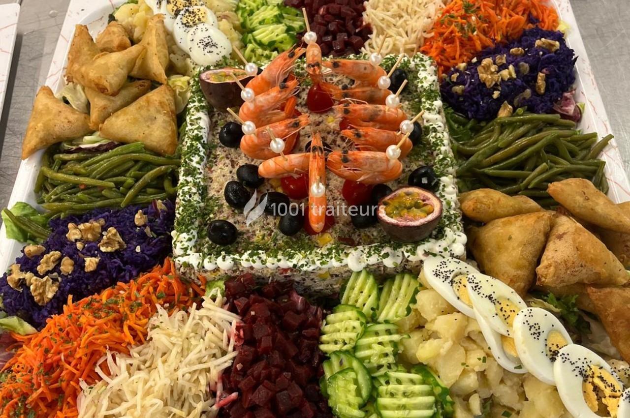 Plateau coloré de crudités, samoussas, crevettes, œufs durs et légumes variés disposés autour d'une garniture centrale.