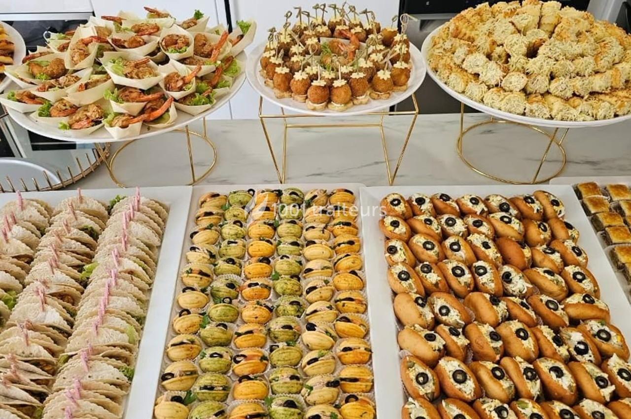 Buffet de pièces apéritives variées disposées sur des plateaux, incluant canapés, bouchées et amuse-bouches.