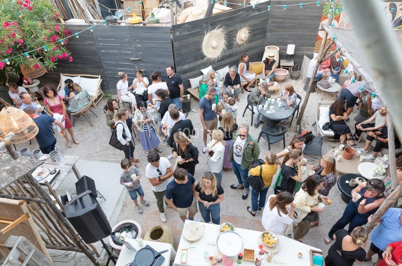 Groupe de personnes réunies dans une cour extérieure décorée, discutant et partageant un moment convivial.