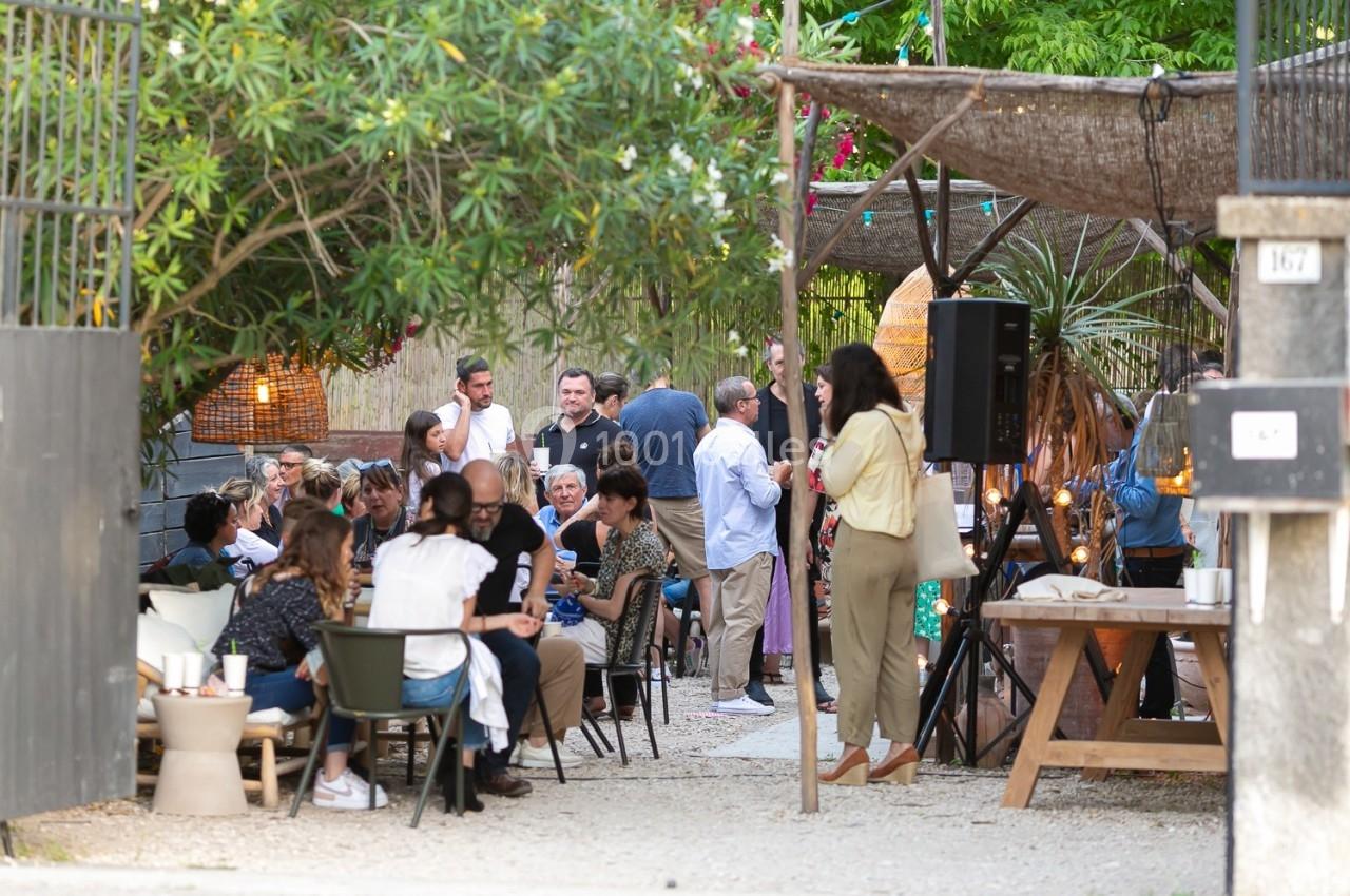 Groupe de personnes rassemblées dans une cour extérieure, discutant et partageant un moment convivial.