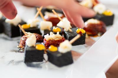 Une main verse du vin blanc dans un verre transparent, avec des bouteilles en arrière-plan flou.