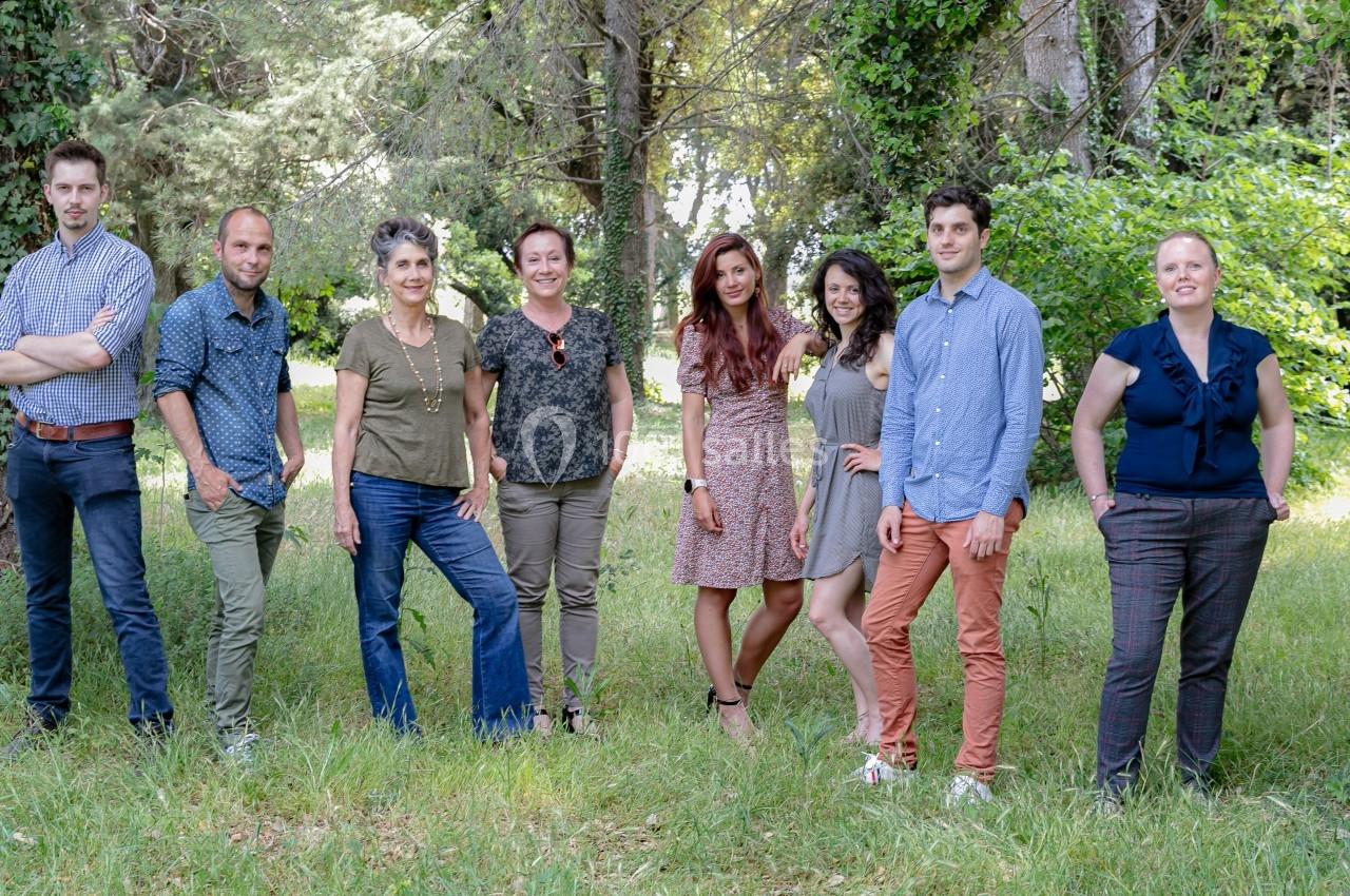 Un groupe de huit personnes debout dans un espace extérieur verdoyant, entouré d'arbres et de végétation.