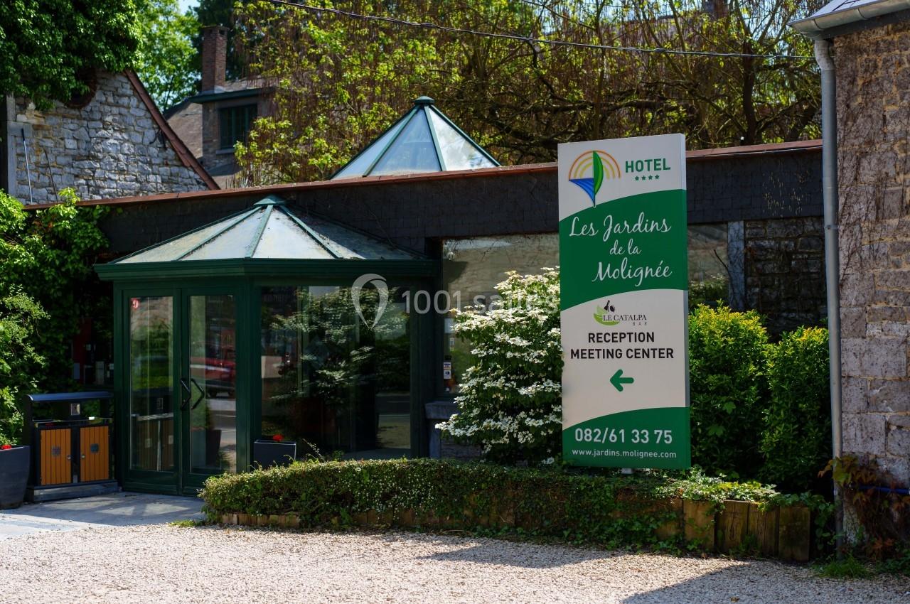 Entrée d'un hôtel avec une enseigne indiquant ’Les Jardins de la Molignée’, réception et centre de réunion.